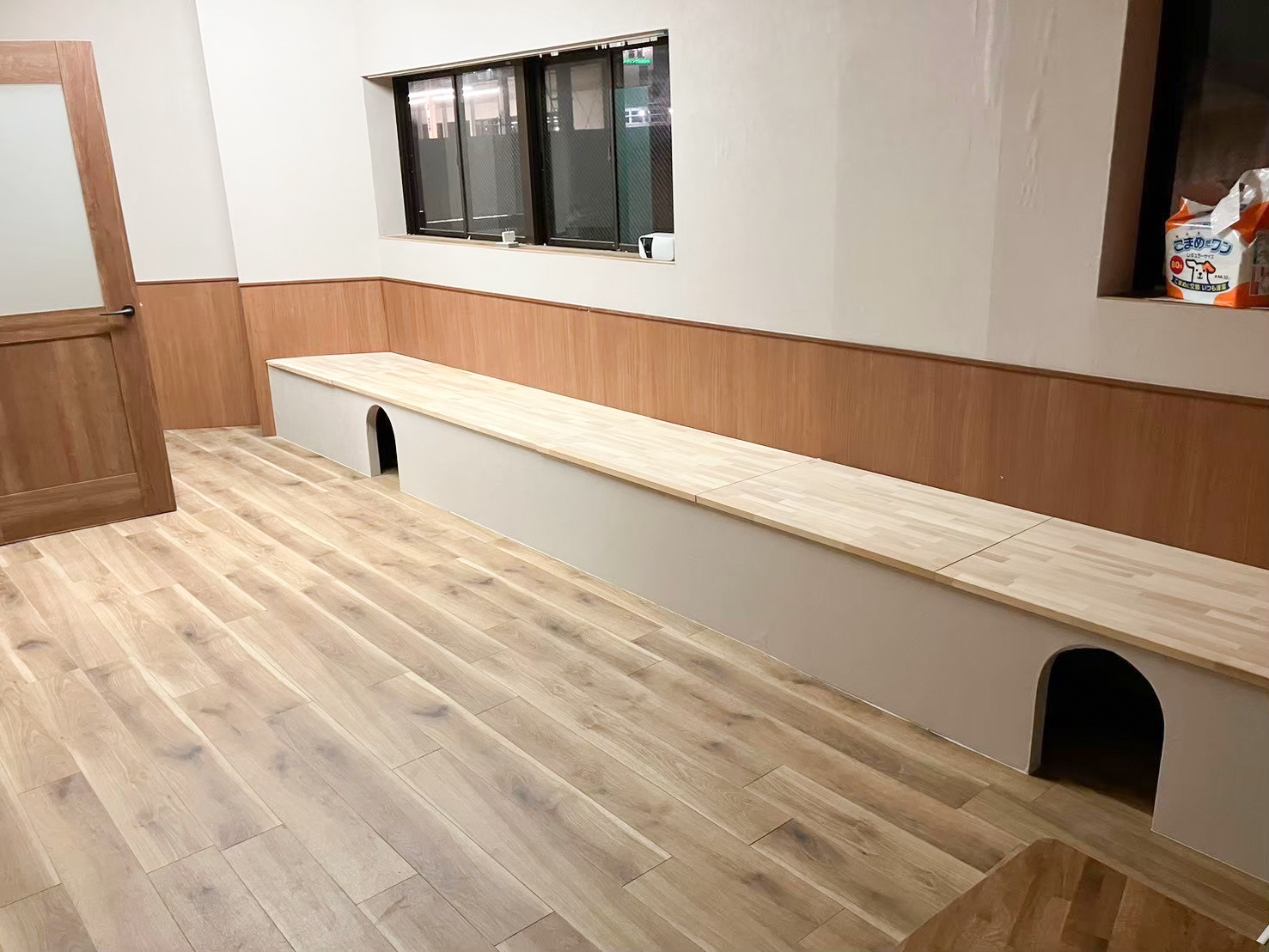 高槻市の猫カフェ造作ベンチ事例。集成材の天板と、猫が通り抜けられるアーチ型トンネル付きの造作ベンチ|TEAM-R