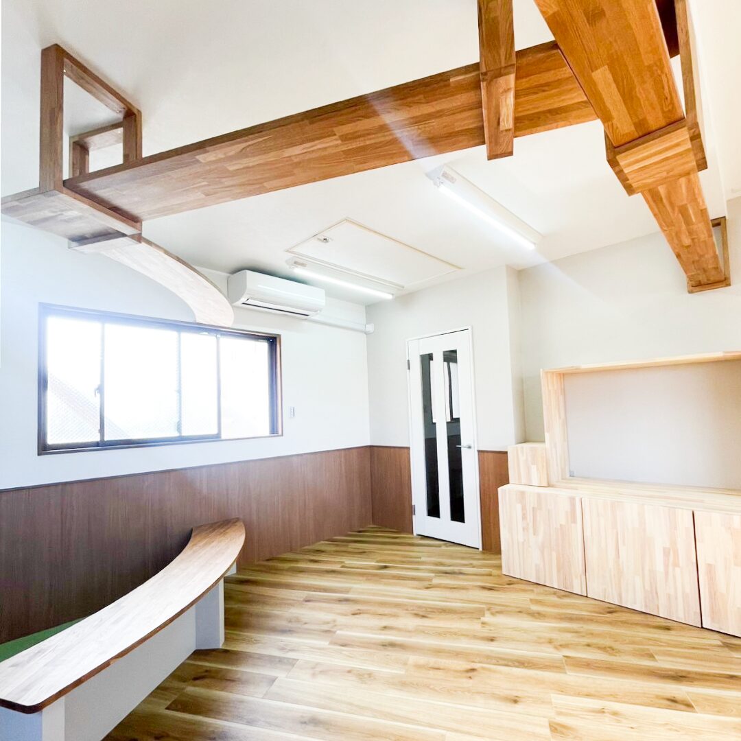 高槻市の猫カフェ内装リフォーム事例。天井を渡る木製キャットウォークと曲線の造作ベンチ、集成材のテレビ台まわり|TEAM-R