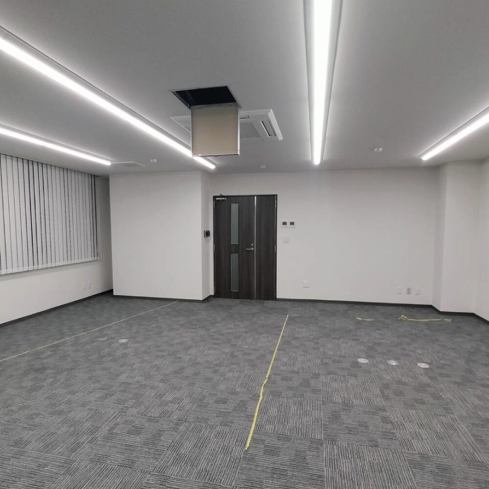 大阪市中央区の店舗リノベーション事例(ビフォー)。バーチカルブラインドの窓とグレーカーペットが残る、施工前のオフィス|造作工事