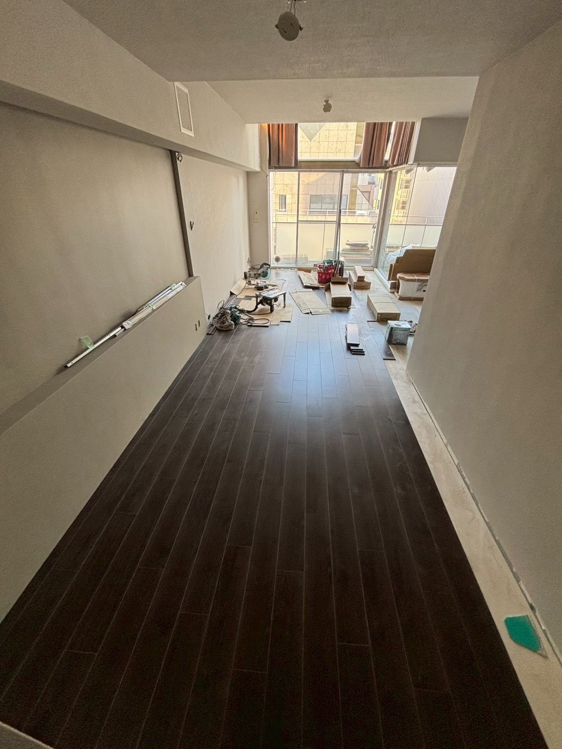 大阪市淀川区のマンションリノベーション事例（施工中）｜ダークブラウンのNODAフローリングを張り進めるリビング｜内装リフォーム