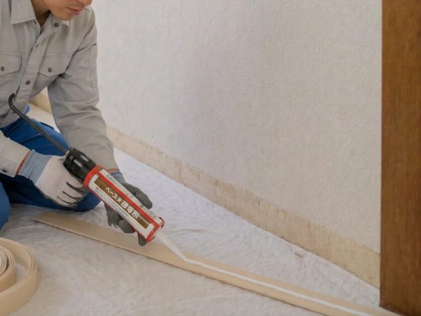 ソフト巾木に接着剤を塗る作業の様子|巾木施工の説明イメージ
