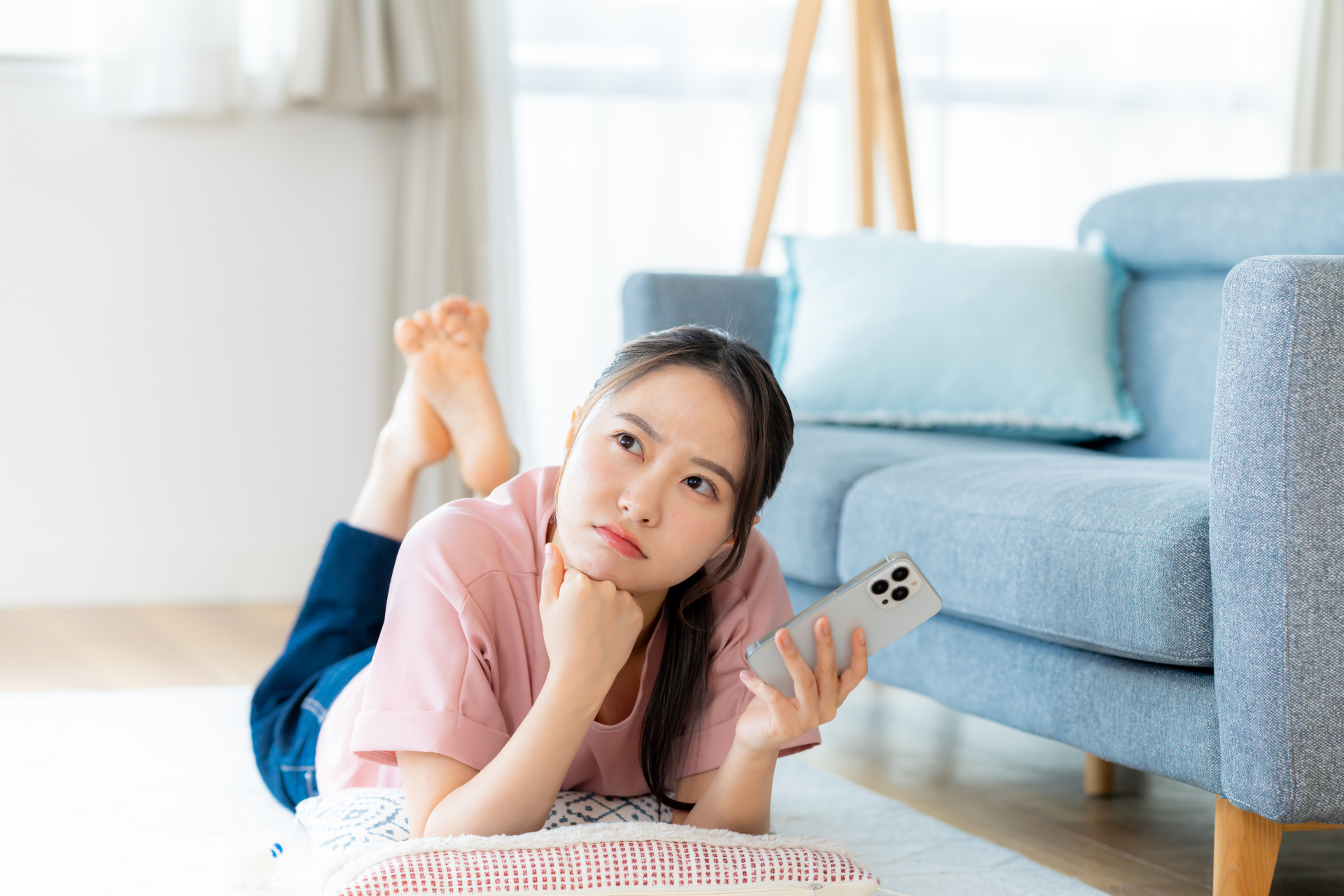 家で寝そべりながら考えている女性の画像